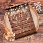 Rustic Wood String Lights Script Wedding Invitation<br><div class="desc">A rustic wedding invitation featuring pretty string lights and a delicate hand-drawn rustic floral garland of botanical leaf foliage with stylish script typography,  on a rustic wood background. Personalise with your special wedding day information. Designed by Thisisnotme©</div>