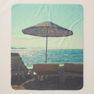Sandy beach on a sunny afternoon,  with parasols a sherpa blanket