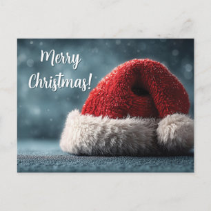 Santa Hat Resting on Snowy Surface with Greeting Holiday Postcard