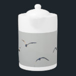 Seagulls Flock Flying<br><div class="desc">Serene image of seagulls flying highlighted by the sun forming light and shade with misty view of mountains in the distance.</div>