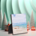 Seas And Greeting Beach Christmas Plaque<br><div class="desc">"Seas And Greeting" holiday saying in beach sand.  Captivating beached fishing boat on a sandy beach with watercolor aqua blue ocean, and sunny sky above.</div>
