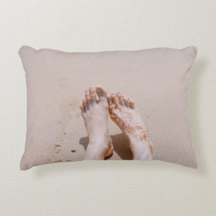 Selective focus photography of feet with tattoo on decorative cushion