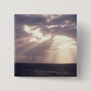 Setting sun shining through clouds over ocean 15 cm square badge