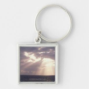 Setting sun shining through clouds over ocean key ring