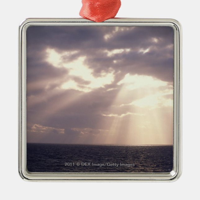 Setting sun shining through clouds over ocean metal ornament (Front)