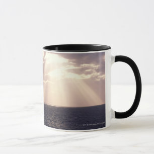 Setting sun shining through clouds over ocean mug
