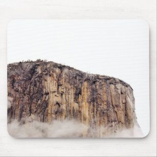 Sheer cliff rising above clouds mouse pad