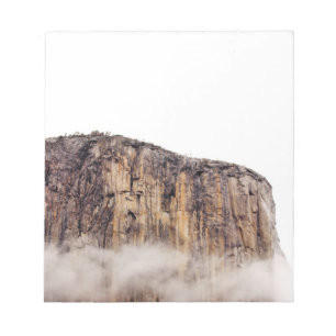 Sheer cliff rising above clouds notepad