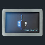 Shiny Blue Dreidel Rectangular Belt Buckle<br><div class="desc">A modernistic,  metallic blue dreidel against a dark,  night-like background.  Two of the Hebrew letters found on a dreidel,  nun and shin,  glow brightly.  Hebrew text reading "Chag Chanukkah Sameach" (Happy Hanukkah) also appears in glowing blue and white.</div>