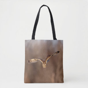 Short-eared owl diving towards the ground tote bag