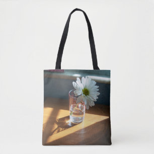 Single white daisy in a sunny spot on a tote bag