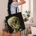 Skeleton with Burning Cigarette | Vincent van Gogh Tote Bag<br><div class="desc">Skull of a Skeleton with Burning Cigarette (1886) by Vincent van Gogh is a striking and unconventional still-life painting that features a human skull with a lit cigarette between its teeth. The dark background enhances the starkness of the skeletal figure, while the small plume of smoke adds a sense of...</div>
