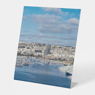 Sliema harbour with modern buildings and boats pedestal sign