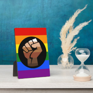 SlipperyJoe's queer people colour flag raised fist Plaque