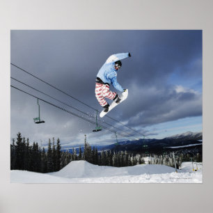 Snowboarder jumping in mid-air doing a backside poster