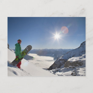 Snowboarder looking from mountain top postcard