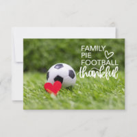 Soccer ball with red heart on green grass