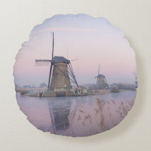 Soft sunrise light in winter over windmills round cushion