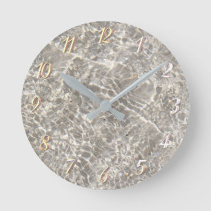 Sparkling water on beach sand round clock