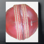 Spin Master's Sphere: A Fun Left Spin Cricket Ball Plaque<br><div class="desc">"Spin Master's Sphere" – A Fun Left Spin Cricket Ball Design This "Spin Master's Sphere" design showcases the iconic red cricket ball, the very instrument wielded by skilled left-arm spin bowlers to weave their magical spells on the pitch. The close-up view highlights the worn texture and crucial stitching that allows...</div>