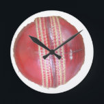 Spin Master's Sphere: A Fun Left Spin Cricket Ball Round Clock<br><div class="desc">"Spin Master's Sphere" – A Fun Left Spin Cricket Ball Design This "Spin Master's Sphere" design showcases the iconic red cricket ball, the very instrument wielded by skilled left-arm spin bowlers to weave their magical spells on the pitch. The close-up view highlights the worn texture and crucial stitching that allows...</div>