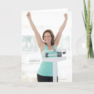Successful weight loss. Happy woman weighing Card