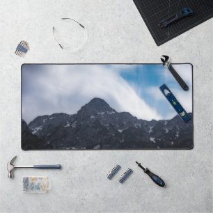 Sun lit green forest beneath the mountains desk mat