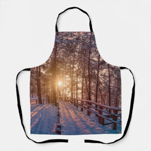 Sunset in snowy pine forest with sun ray apron