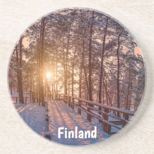 Sunset in snowy pine forest with sun ray coaster