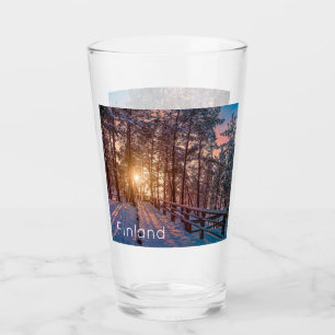Sunset in snowy pine forest with sun ray glass