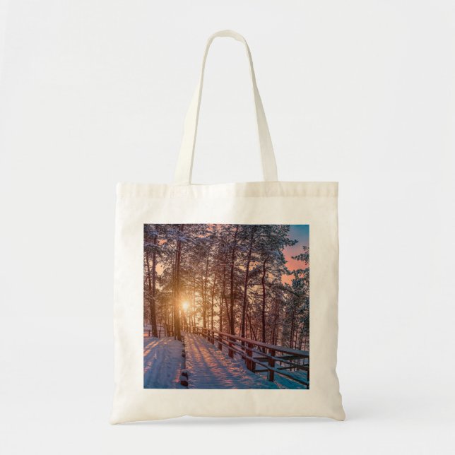 Sunset in snowy pine forest with sun ray tote bag (Front)
