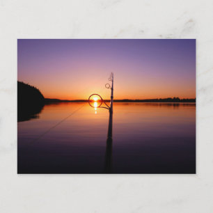 Sunset on a summer lake seen through a fishing rod postcard