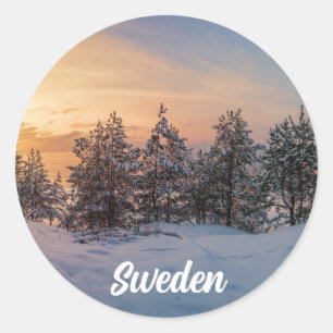Sunset over frozen snowy forest near sea classic round sticker
