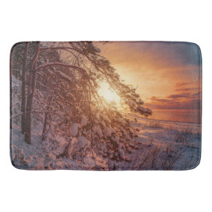 Sunset over sea and snowy pine tree bath mat