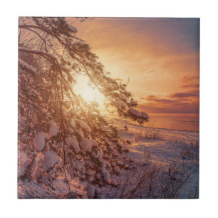 Sunset over sea and snowy pine tree ceramic tile