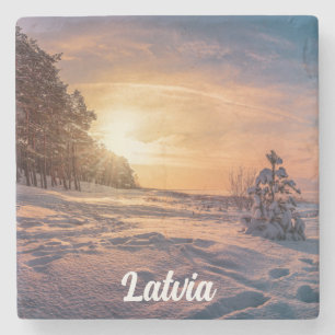 Sunset over snowy winter sea coast stone coaster