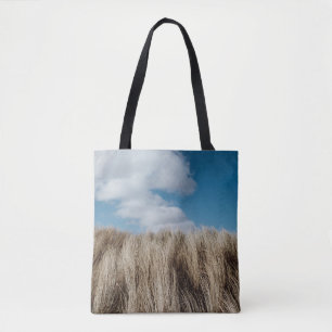Tall grass under cumulus clouds tote bag