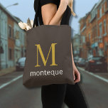 Taupe Elegant Custom Gold Monogram Gift For Her Tote Bag<br><div class="desc">Custom Tote Bag with a bold metallic gold initial and subtle surname below. The taupe background adds warmth and sophistication while keeping a modern aesthetic. Ideal as a personalized gift for women who love understated luxury and neutral fashion.</div>