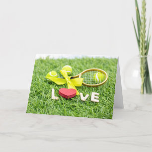 Tennis ball and racket on green grass with love   holiday card