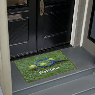Tennis racket with ball on green grass doormat