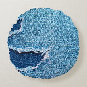 Textured denim background. Torn hole in the fabric Round Cushion
