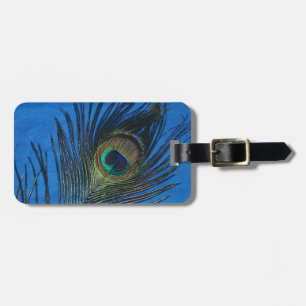 The metallic pink background with the vibrant peac luggage tag