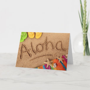 The word Aloha written on a sandy beach, with 2 Card