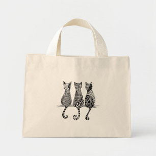 Three Black and white cats on a bag