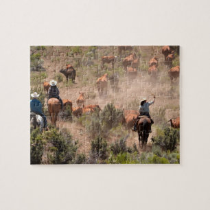 Three cowboys and cowgirls driving cattle jigsaw puzzle
