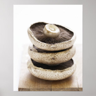 Three flat mushrooms in pile on wooden board, poster