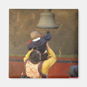 Tibetan Buddhist monk lifting a boy to ring a Magnet