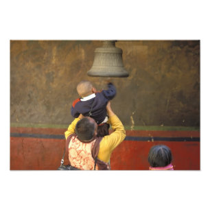 Tibetan Buddhist monk lifting a boy to ring a Photo Print
