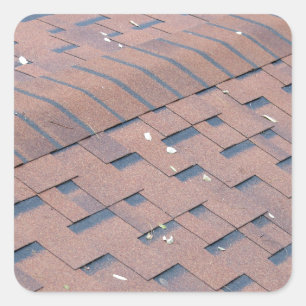 Top view of brown roof shingles with a few fallen square sticker