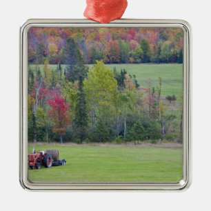 Tractor with hay bale in green field with metal ornament